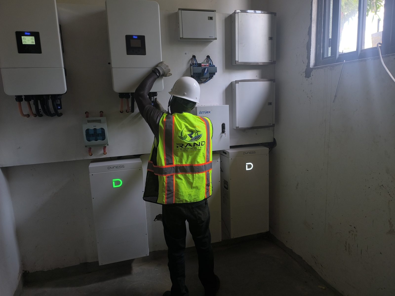 Rand Energies technician servicing a Deye hybrid inverter
